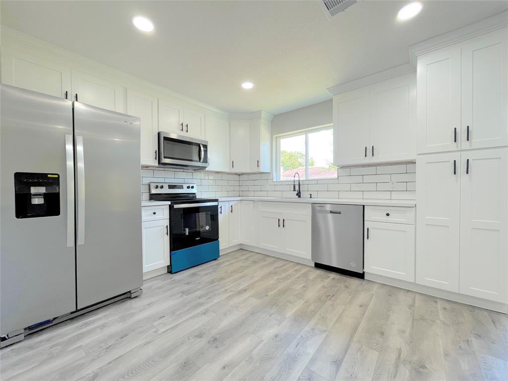 a kitchen with stainless steel appliances granite countertop a stove top oven a sink and a refrigerator