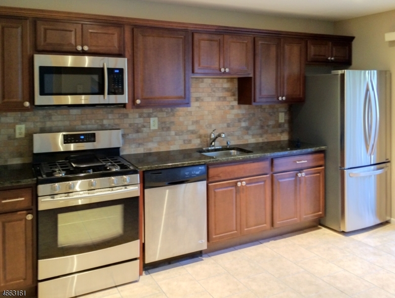 a kitchen with granite countertop wooden cabinets stainless steel appliances and a counter space