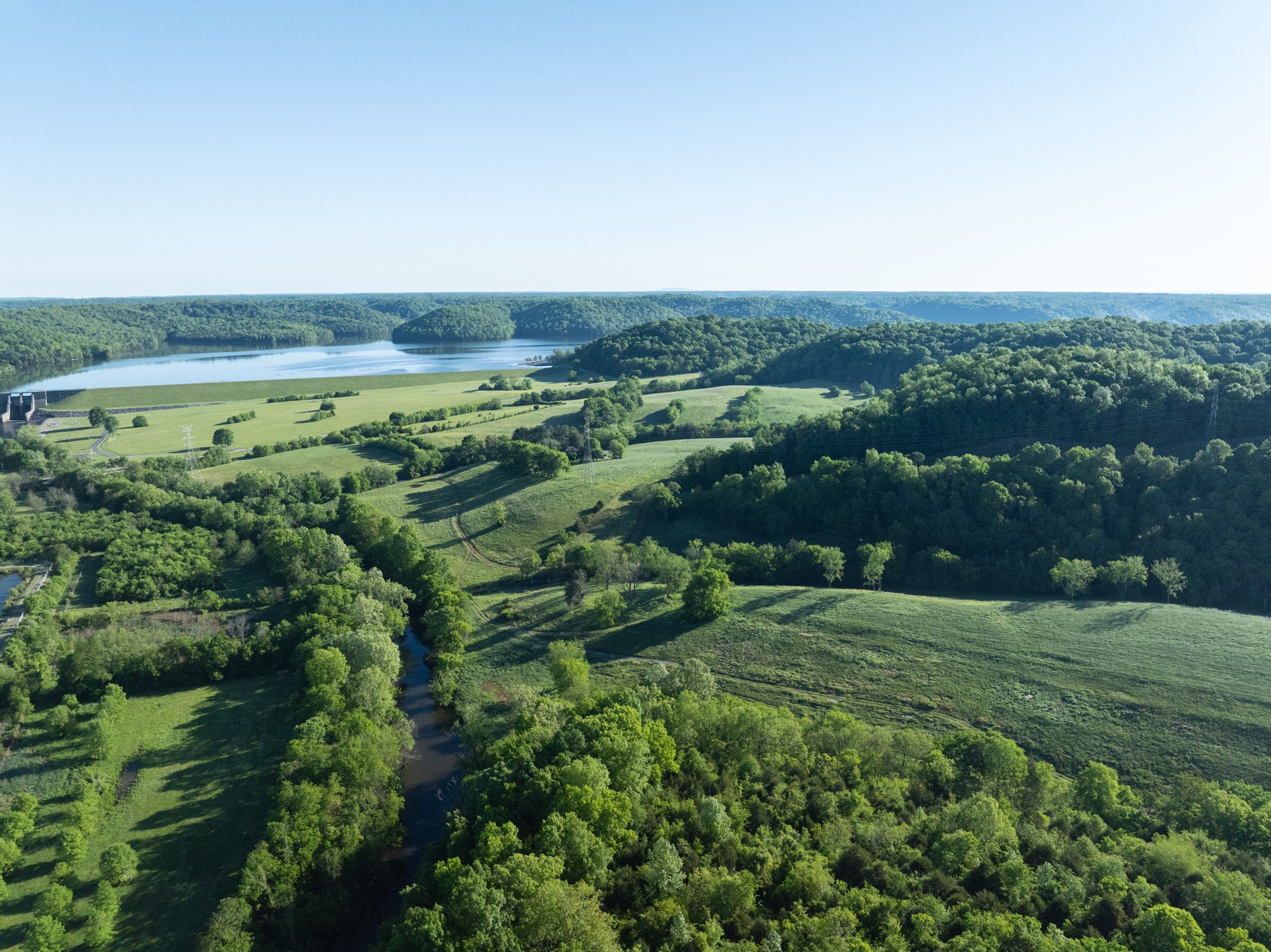 an aerial view of field with trees in background