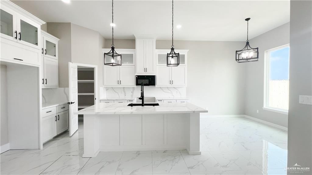 Kitchen with a kitchen island with sink and white cabinets