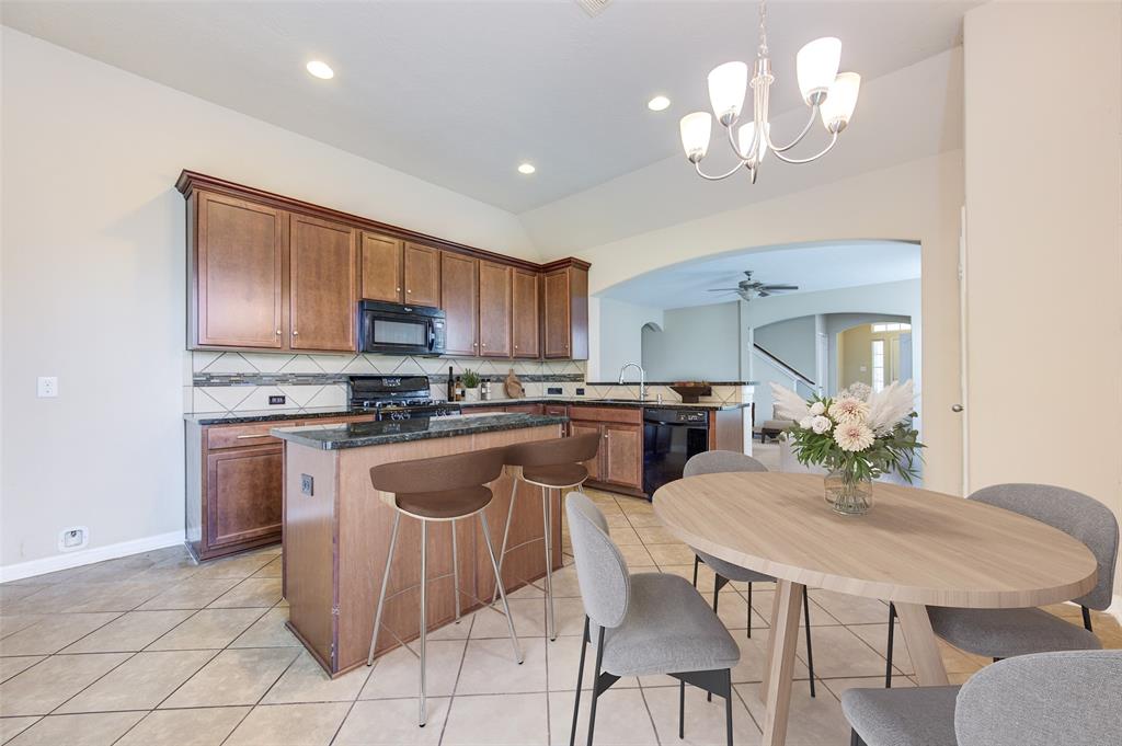 a kitchen with stainless steel appliances granite countertop a sink a stove a dining table and chairs