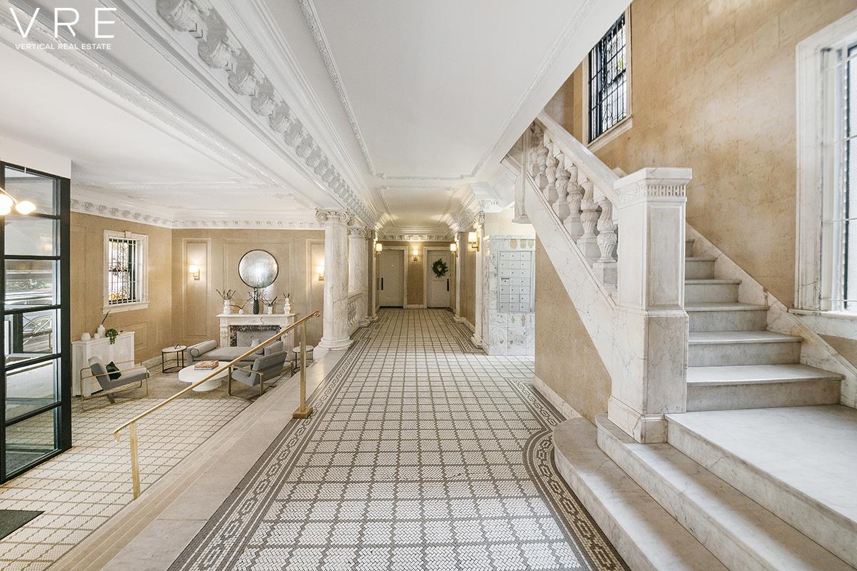 a view of a hallway to a livingroom with wooden floor and furniture