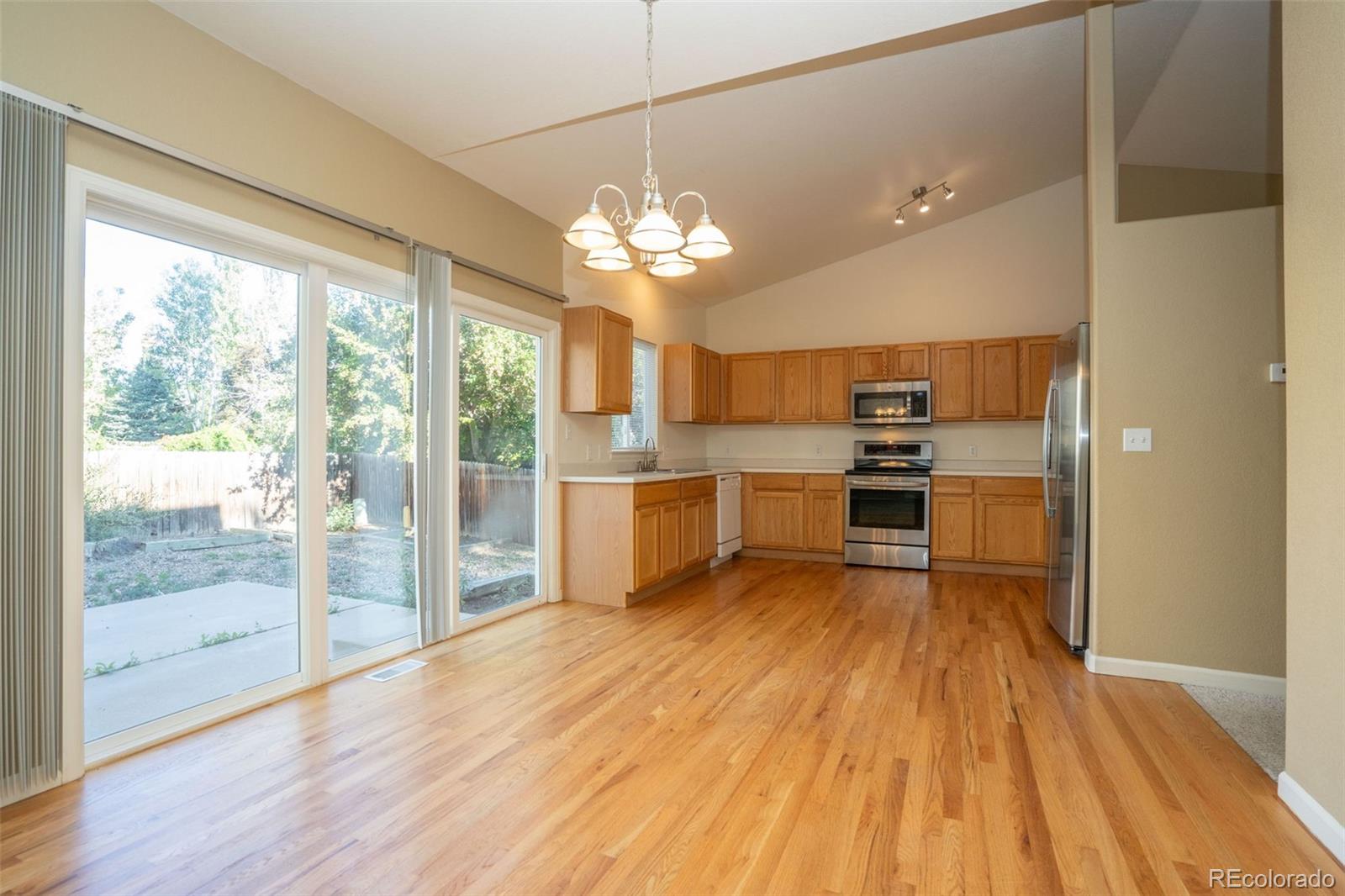 a view of a kitchen with wooden floor a refrigerator a sink and dishwasher