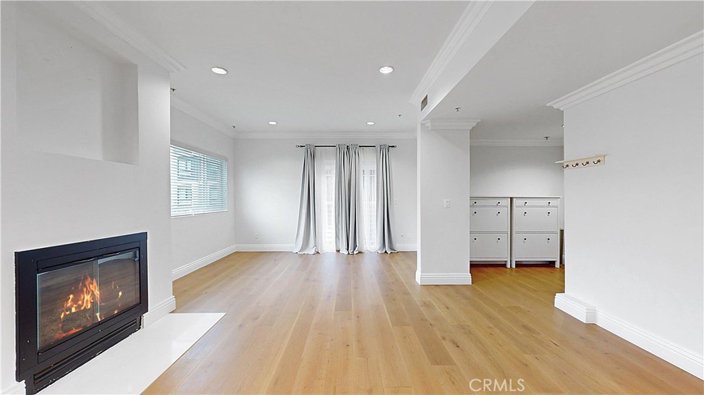 a view of empty room with wooden floor and kitchen