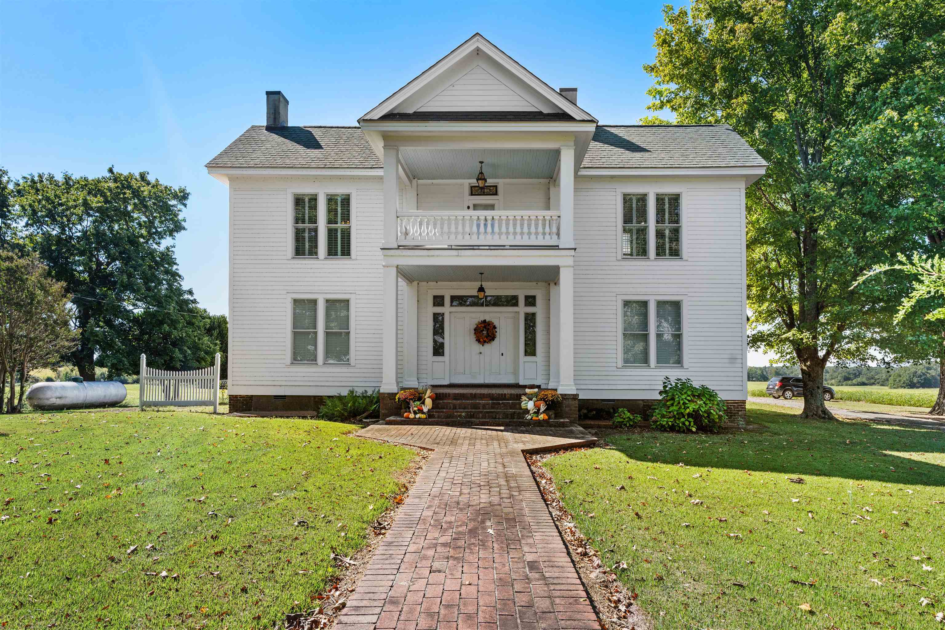 View of front of home with a balcony, ceiling fan, and a front yard