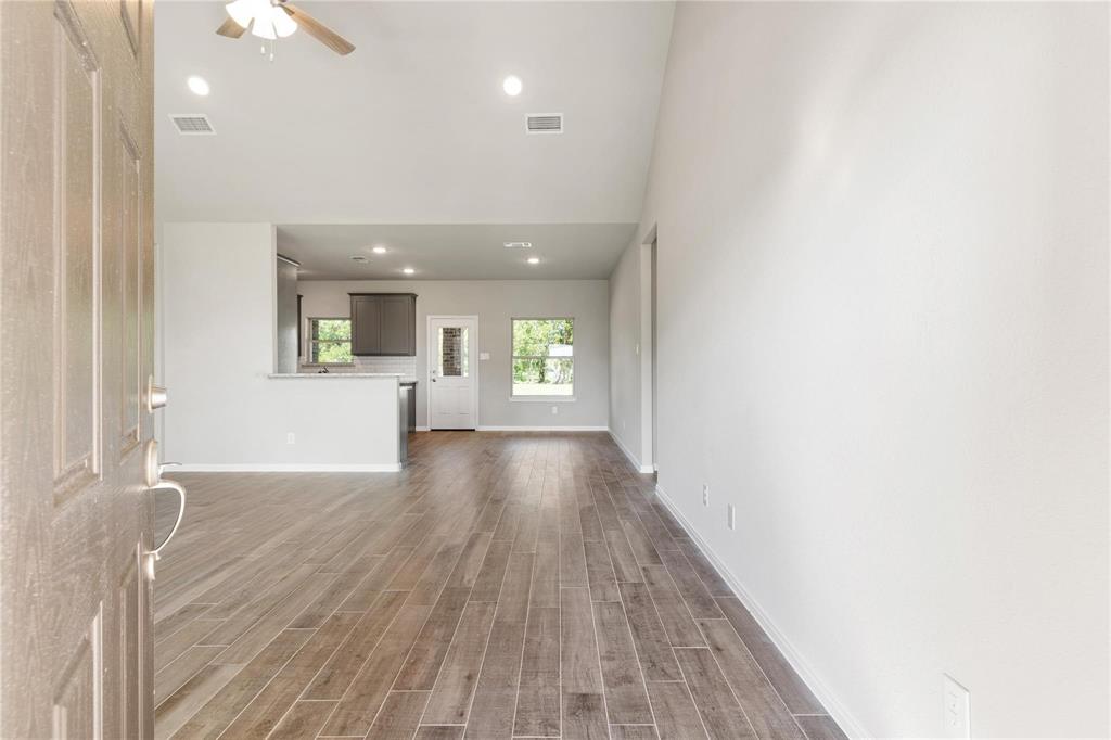 a view of an empty room and a kitchen with wooden floor and a kitchen