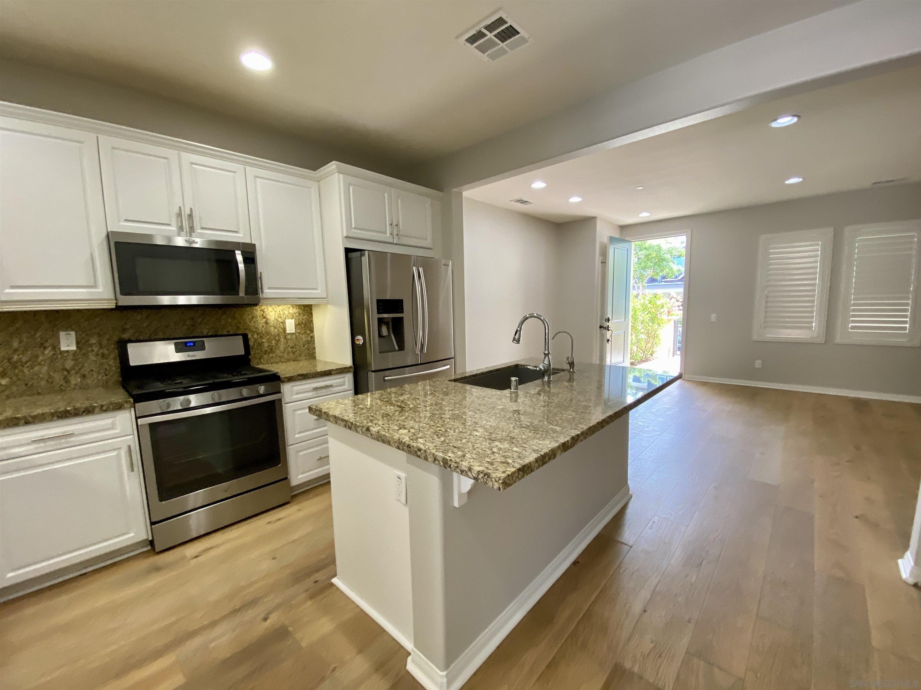 a kitchen with stainless steel appliances kitchen island granite countertop a stove a sink and a microwave