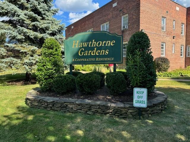 a sign board with a small yard and large trees