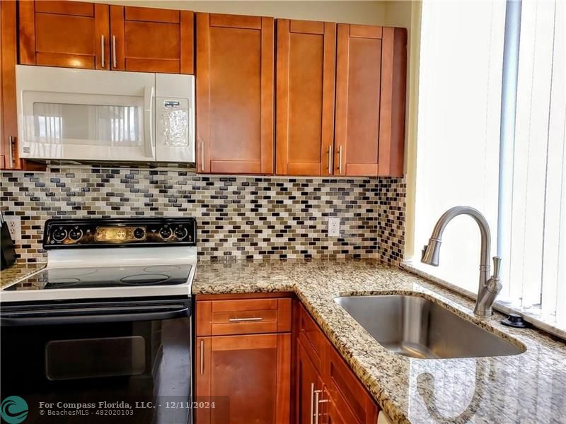 a kitchen with granite countertop a sink stove and cabinets