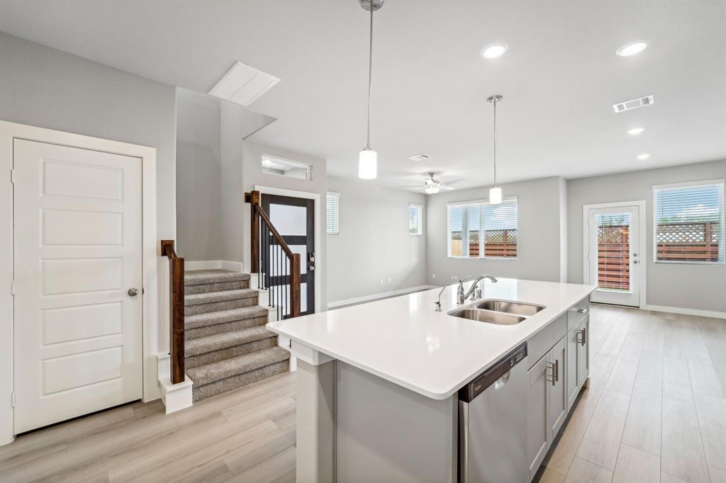 a kitchen with a sink a center island wooden floor and a view of kitchen