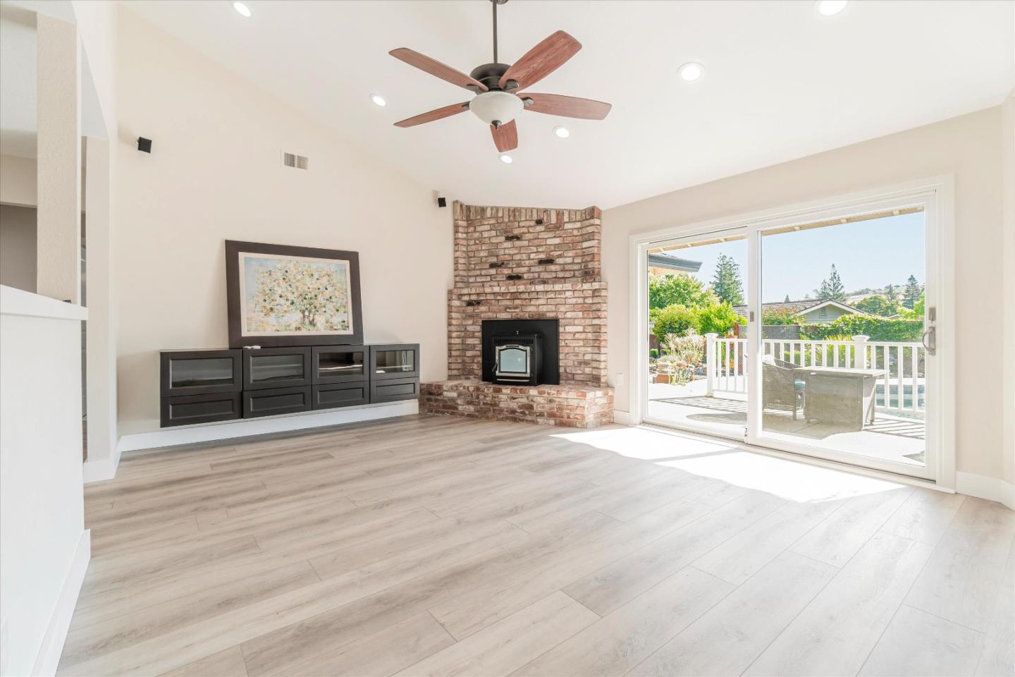 a view of a livingroom with a fireplace a ceiling fan and windows