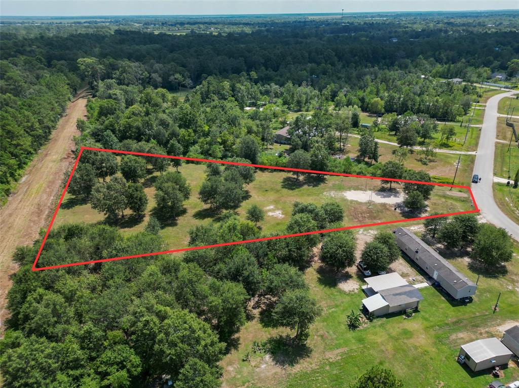 an aerial view of residential house with outdoor space and trees all around