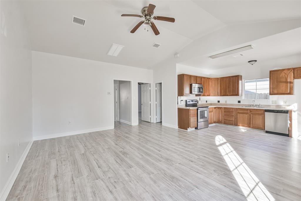 a large kitchen with a wooden floor and stainless steel appliances