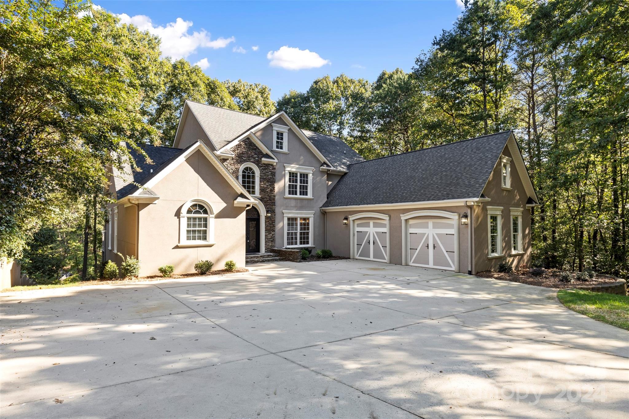 a front view of a house with a big yard and large trees