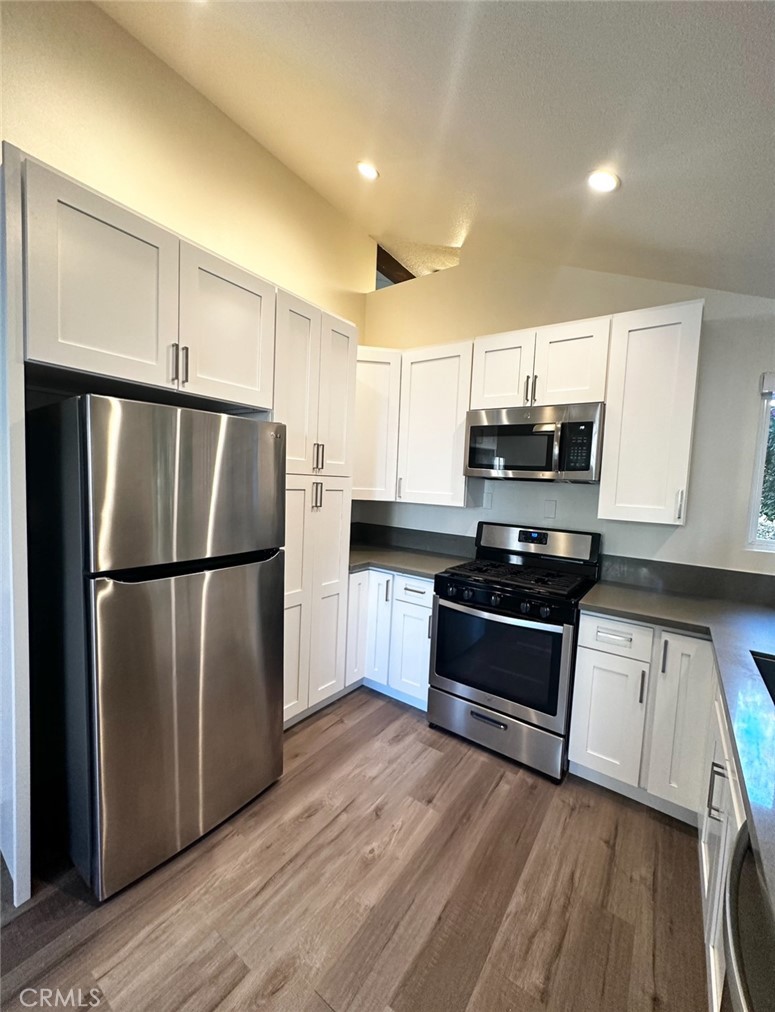 a kitchen with kitchen island granite countertop a refrigerator and a stove top oven