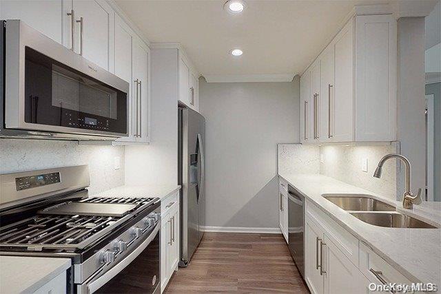 a kitchen with stainless steel appliances a sink a stove a microwave and cabinets