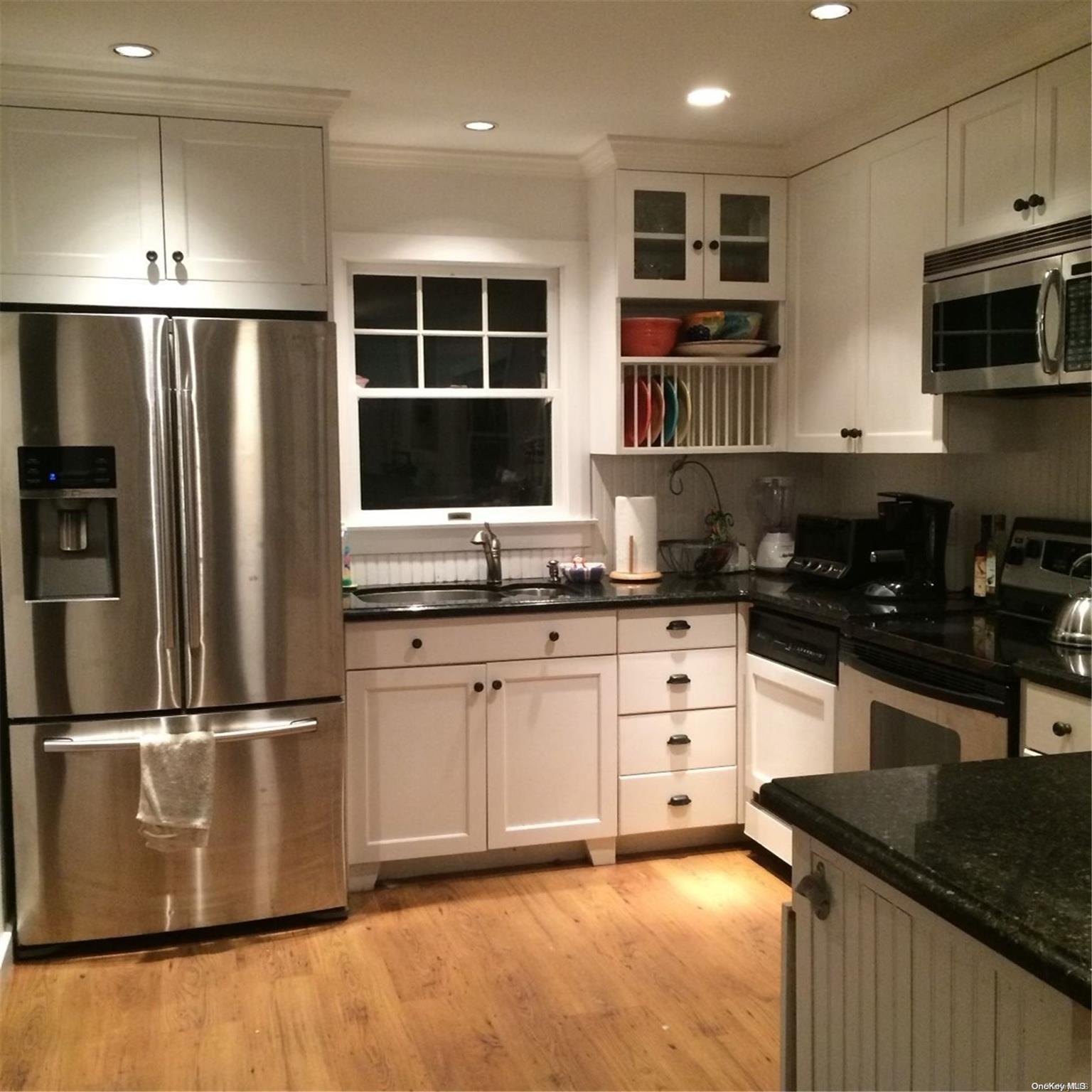 a kitchen with granite countertop a refrigerator and a stove top oven