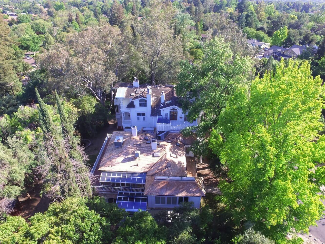 an aerial view of a house with a yard and large trees