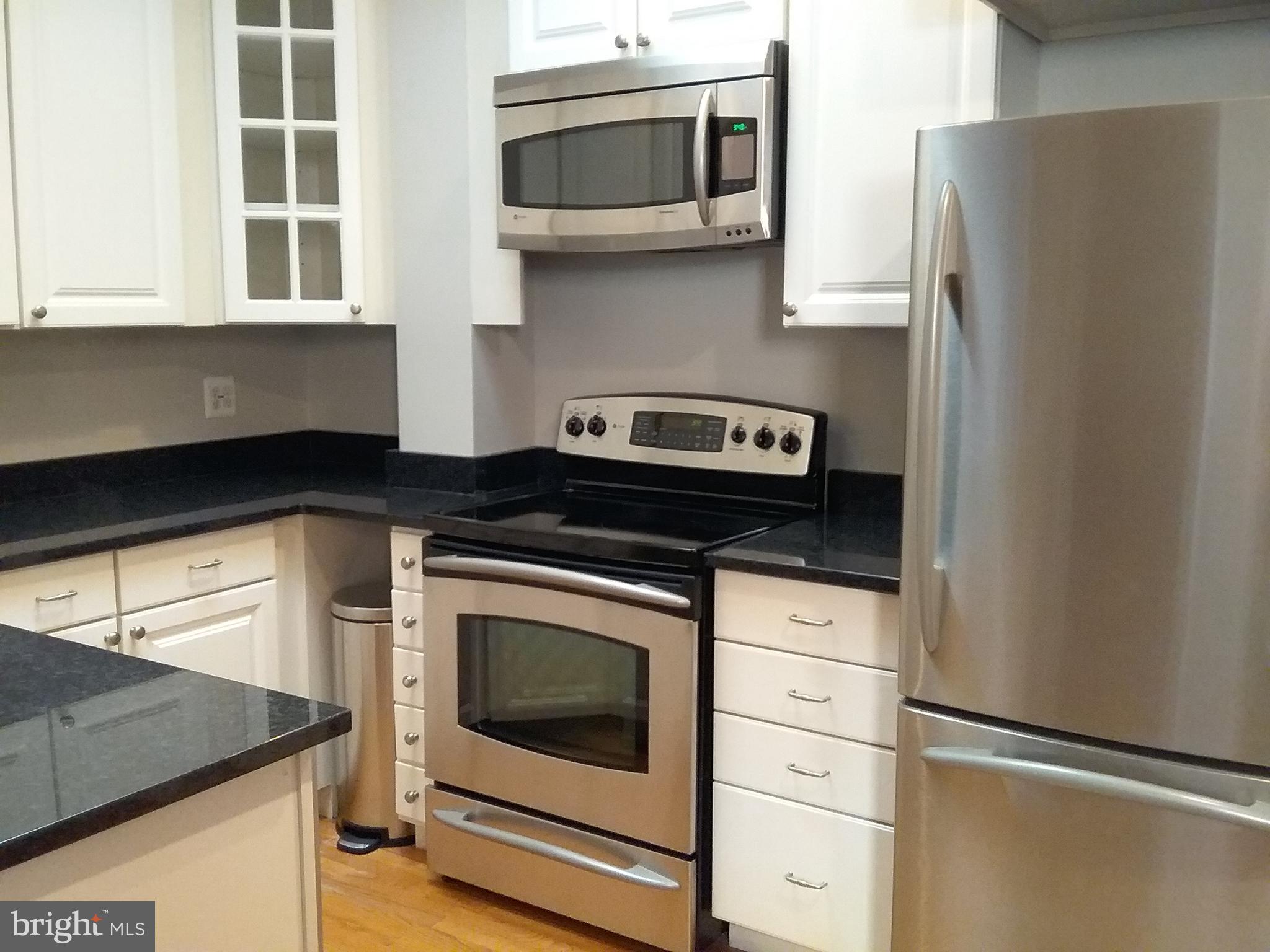 a kitchen with stainless steel appliances granite countertop white cabinets and a stove