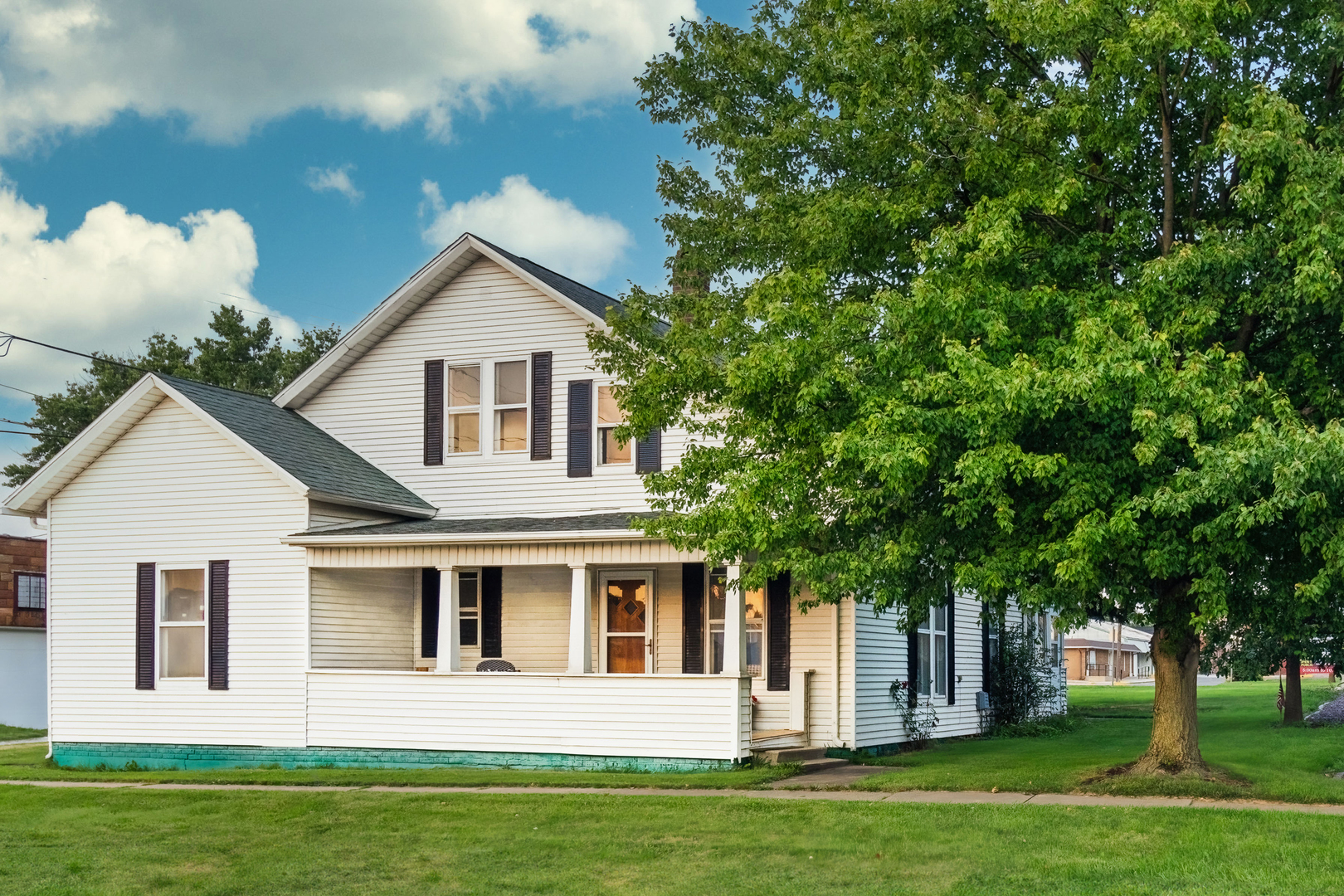 a front view of a house with a garden and trees