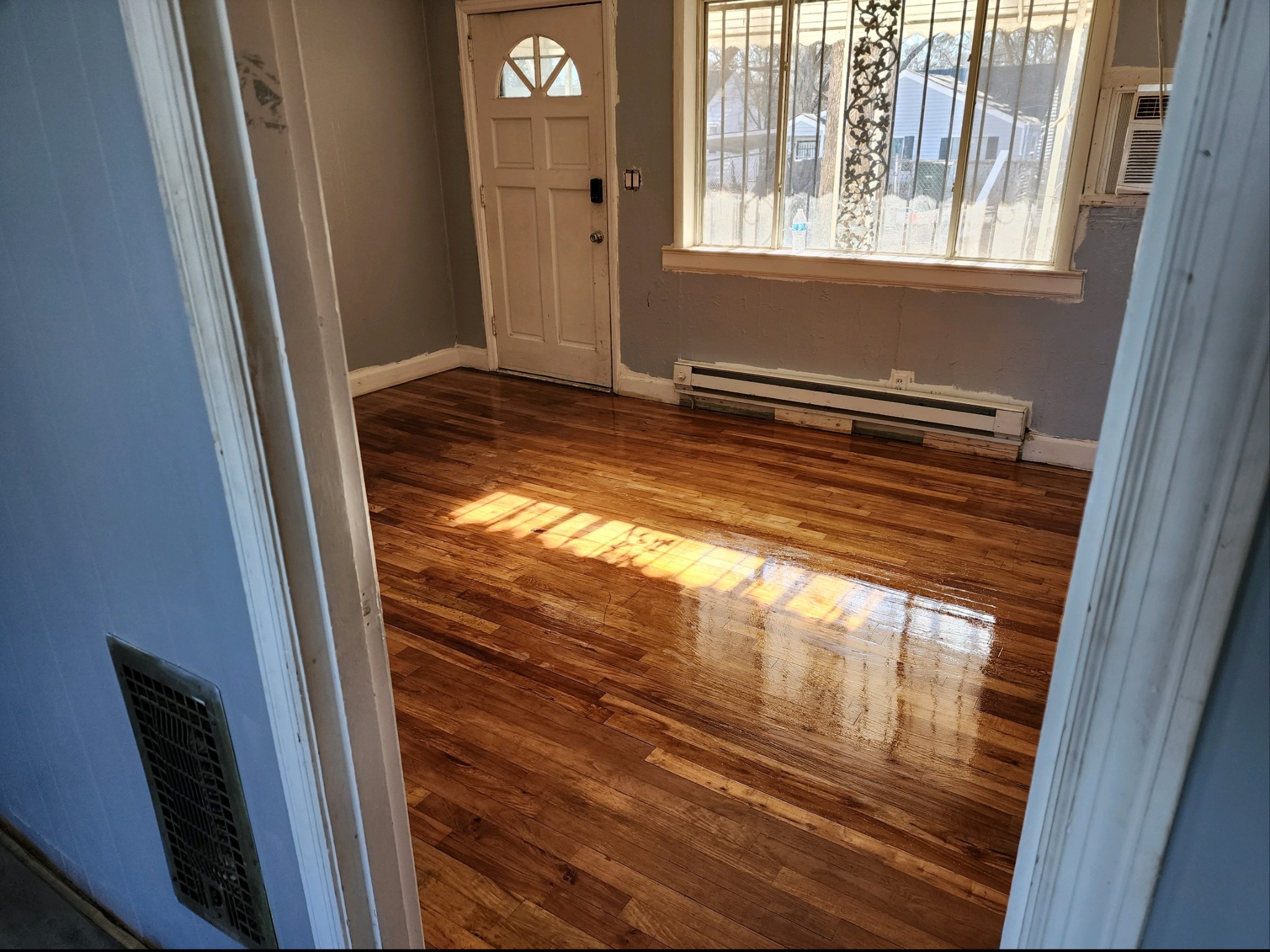 a view of an empty room with wooden floor and a window