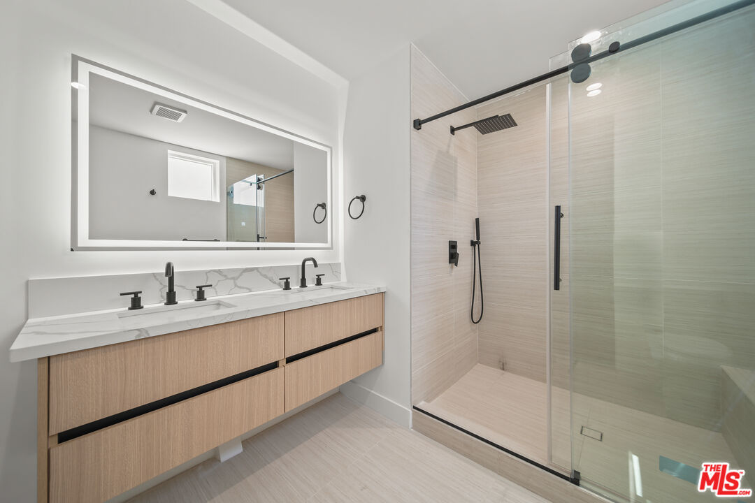 a bathroom with a double vanity sink mirror and shower