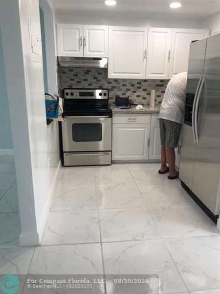 a kitchen with granite countertop a stove top oven and cabinets