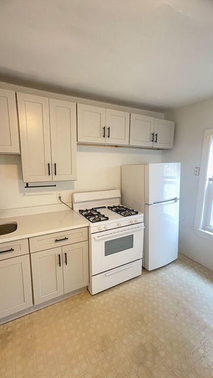 a kitchen with granite countertop white cabinets and white appliances