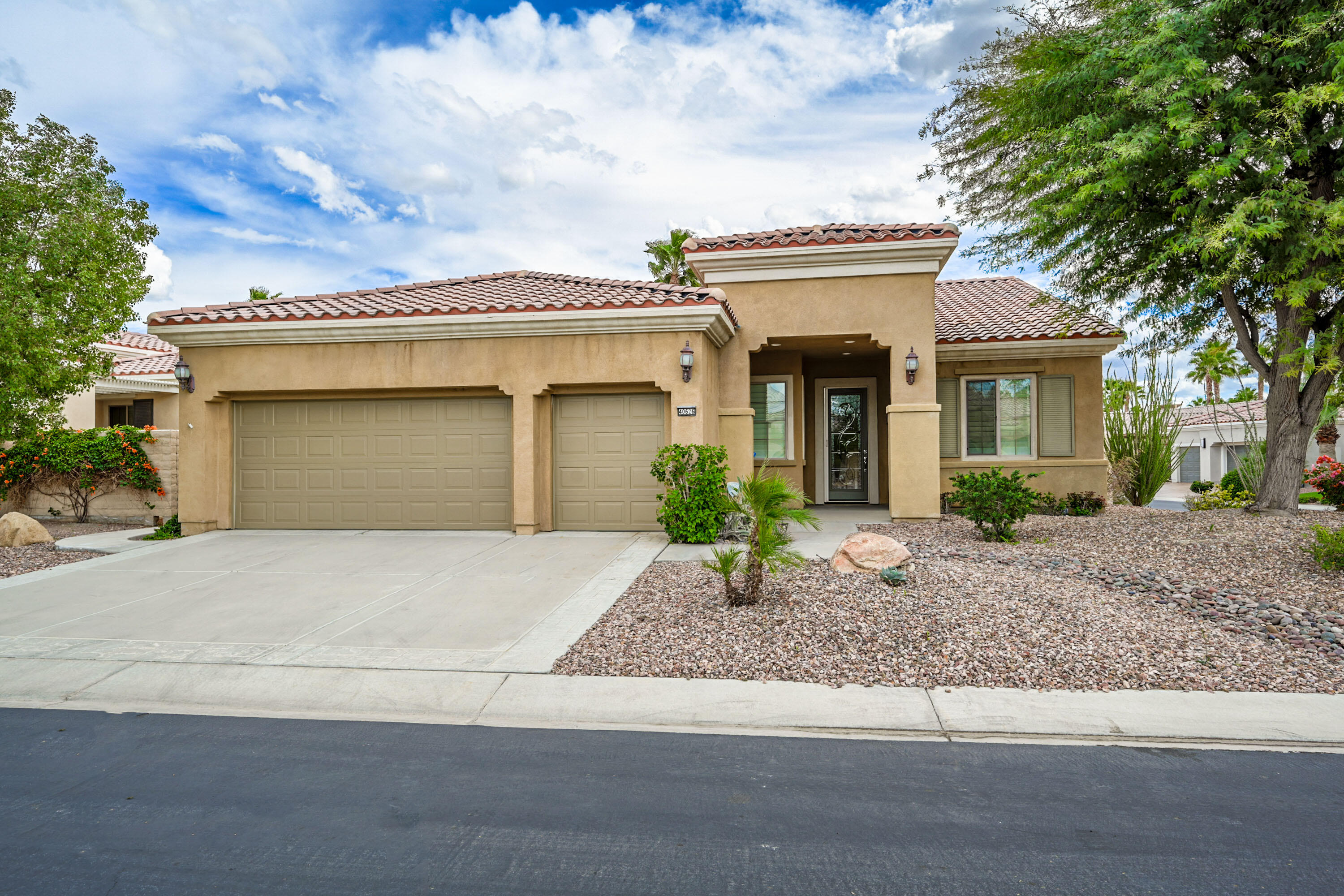 a front view of a house with garage and plants