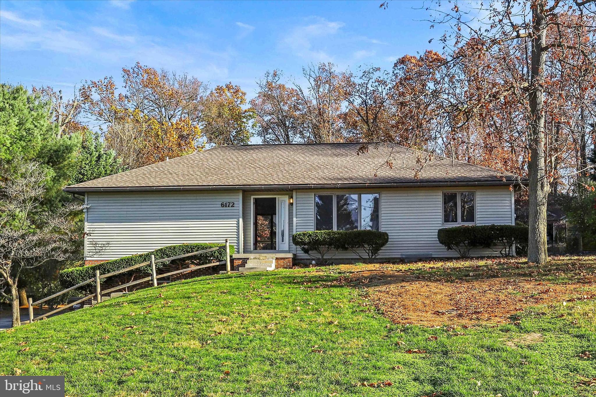 a front view of house with yard and trees in the background