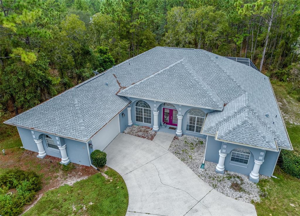 an aerial view of a house with a yard and large trees