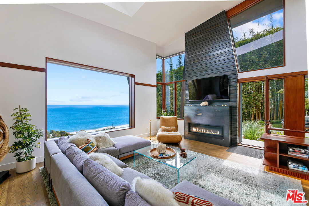 a living room with furniture a flat screen tv and a floor to ceiling window