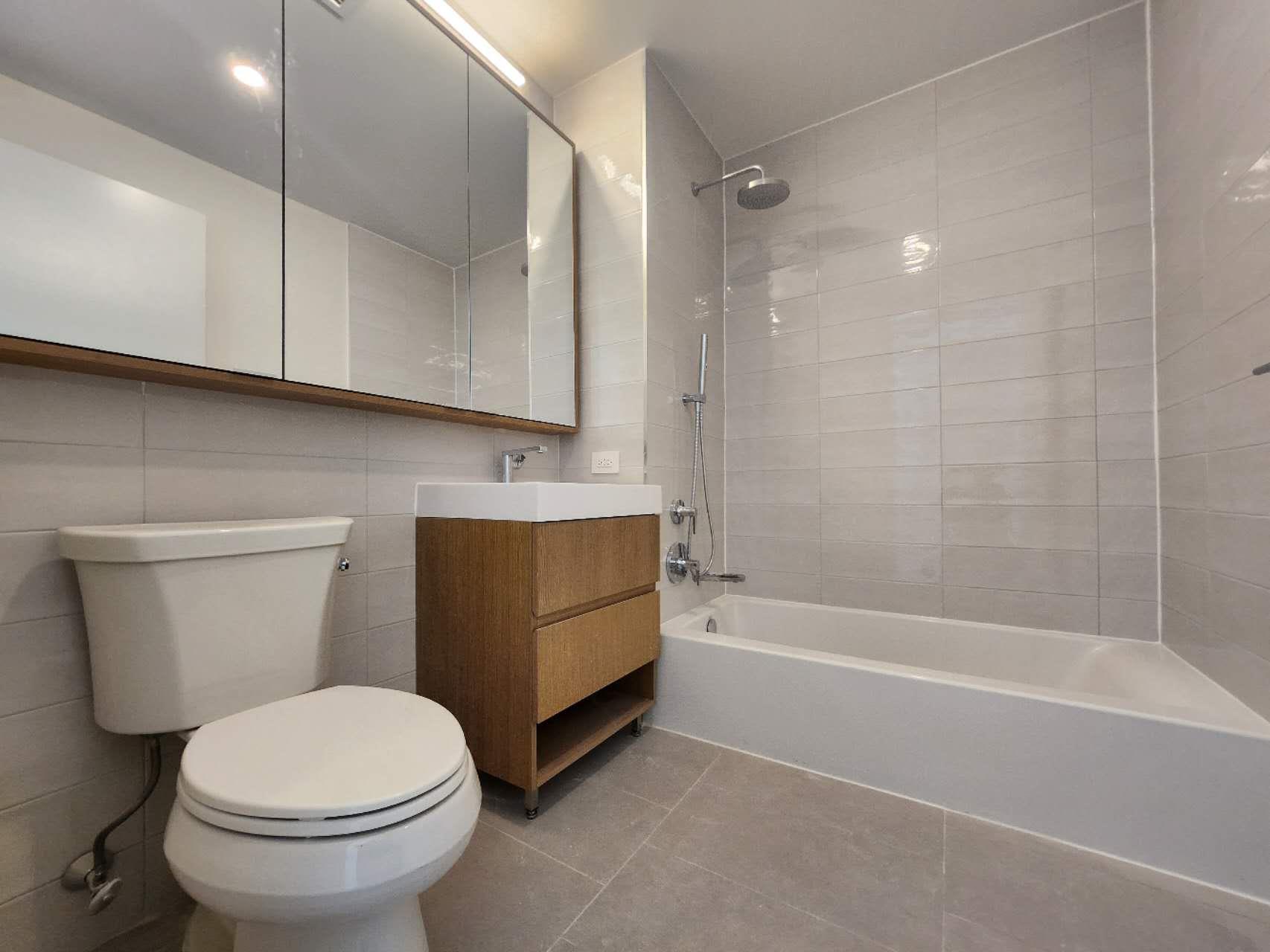 Full bathroom with tile patterned floors, toilet, vanity, tile walls, and tiled shower / bath