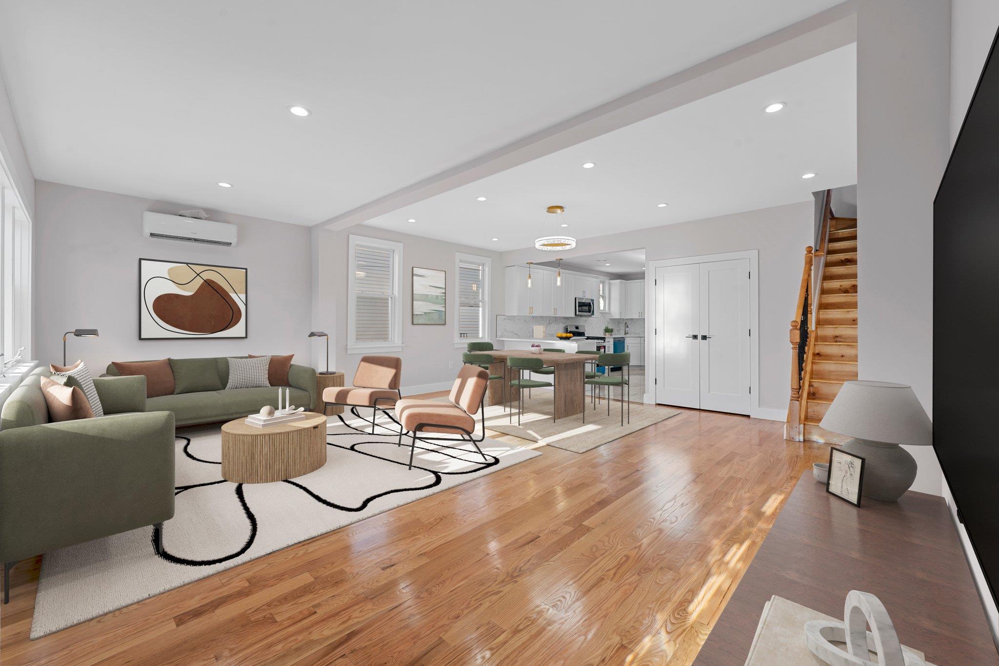 Living room featuring a wall mounted air conditioner, plenty of natural light, and light wood-type flooring