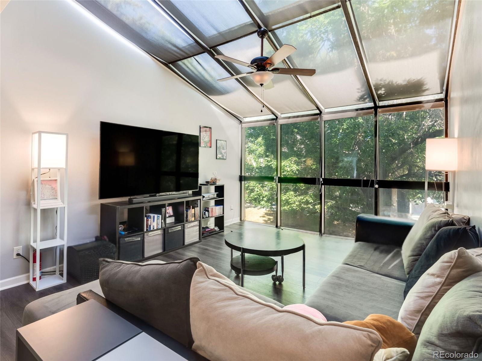 a living room with furniture a flat screen tv and a floor to ceiling window