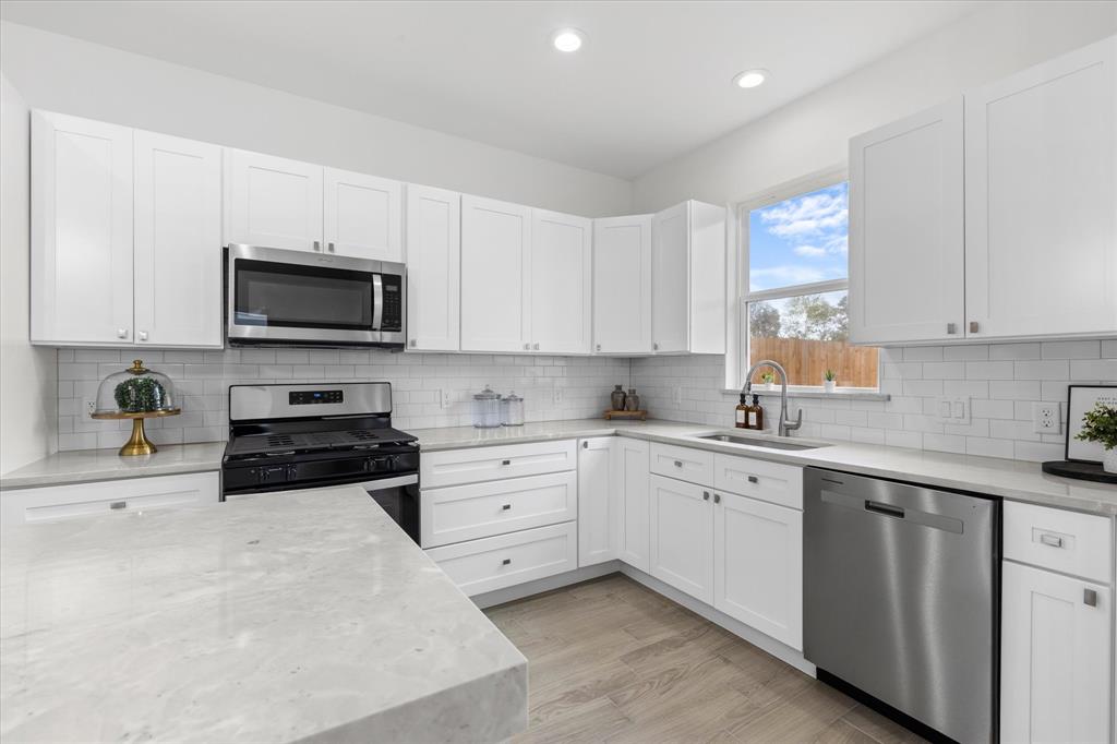 a kitchen with cabinets stainless steel appliances a sink and a window