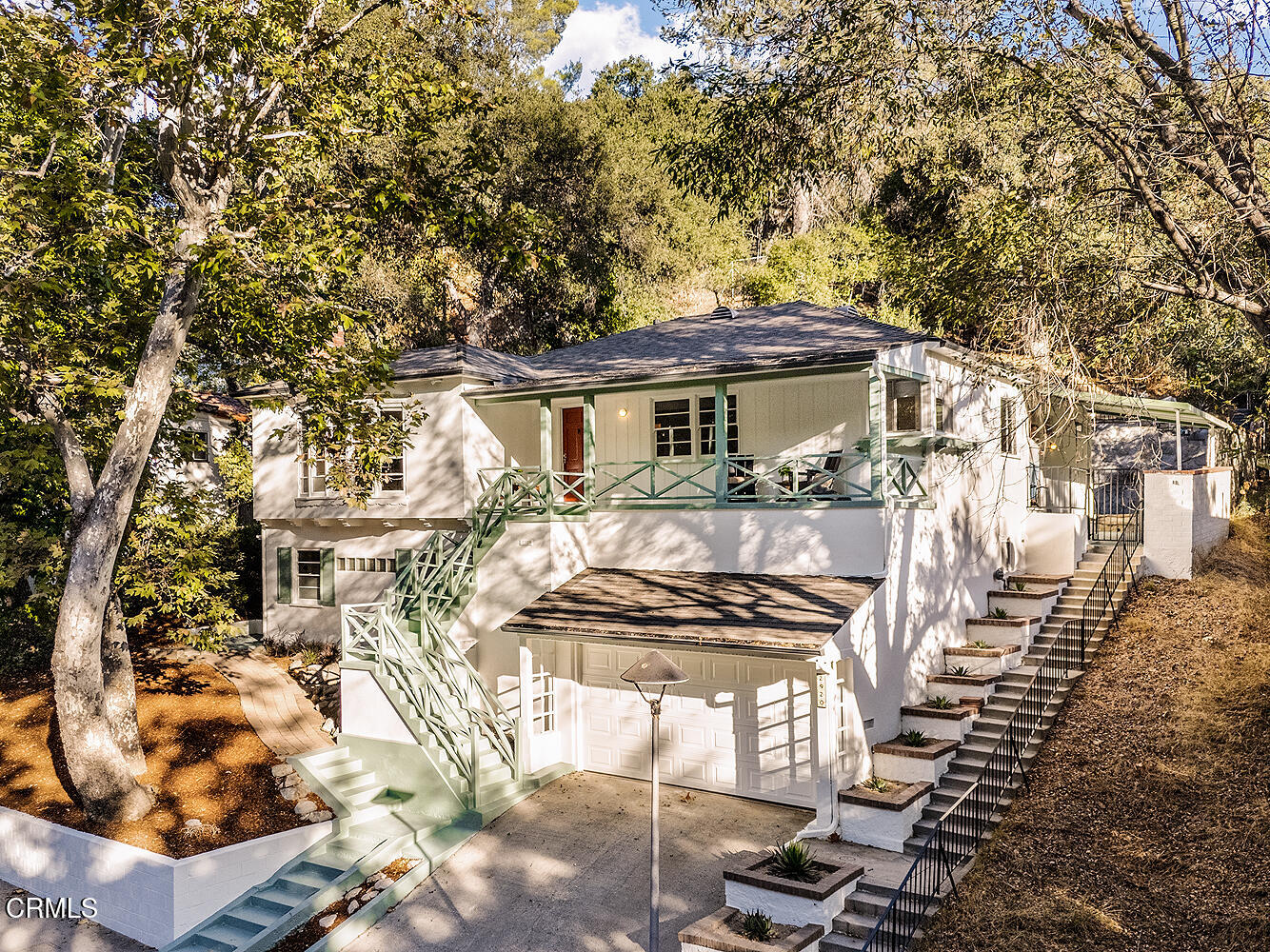 a view of a white house with large trees and outdoor seating