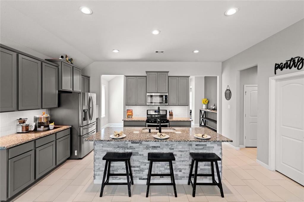 a kitchen with kitchen island granite countertop a sink and refrigerator