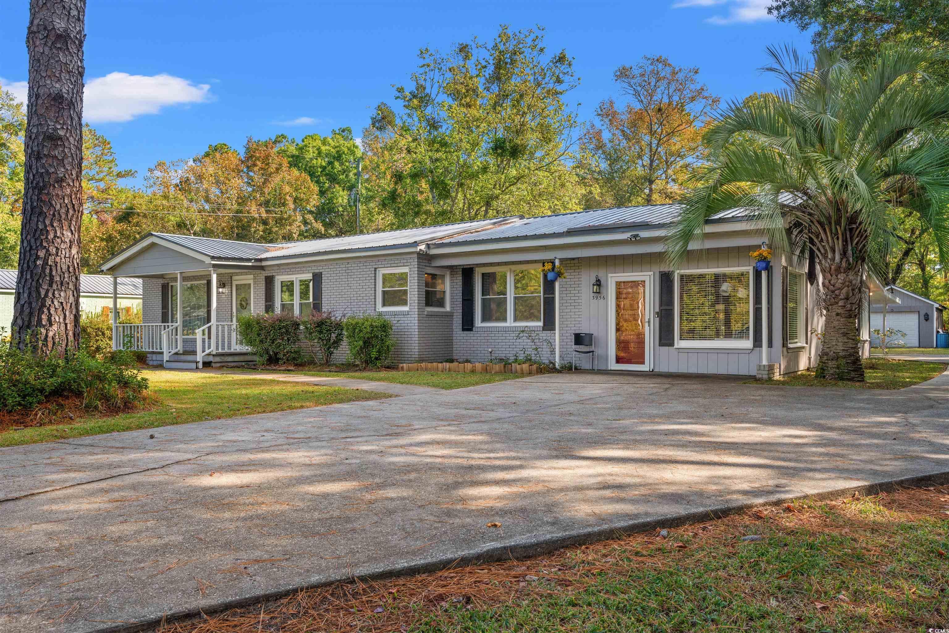 Ranch-style home featuring covered porch and a gar