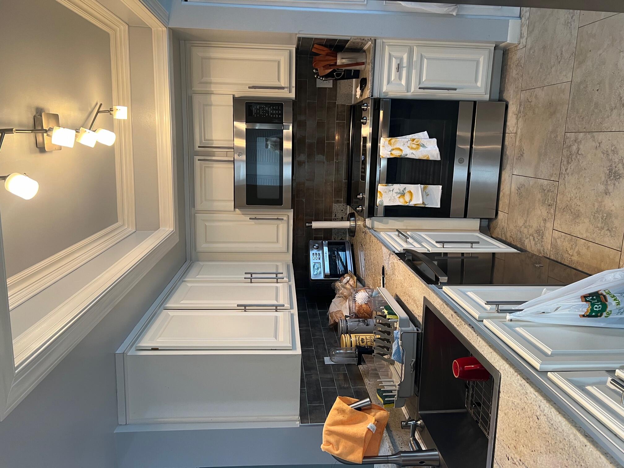 a kitchen with kitchen island granite countertop a sink cabinets and stainless steel appliances