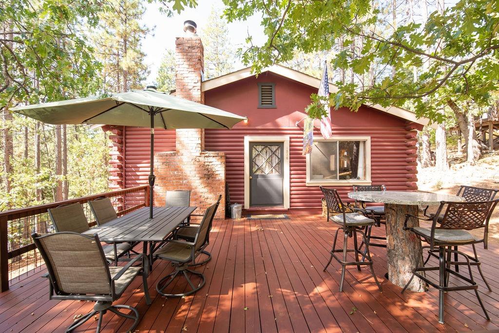 a view of a patio with table and chairs under an umbrella with wooden floor and fence