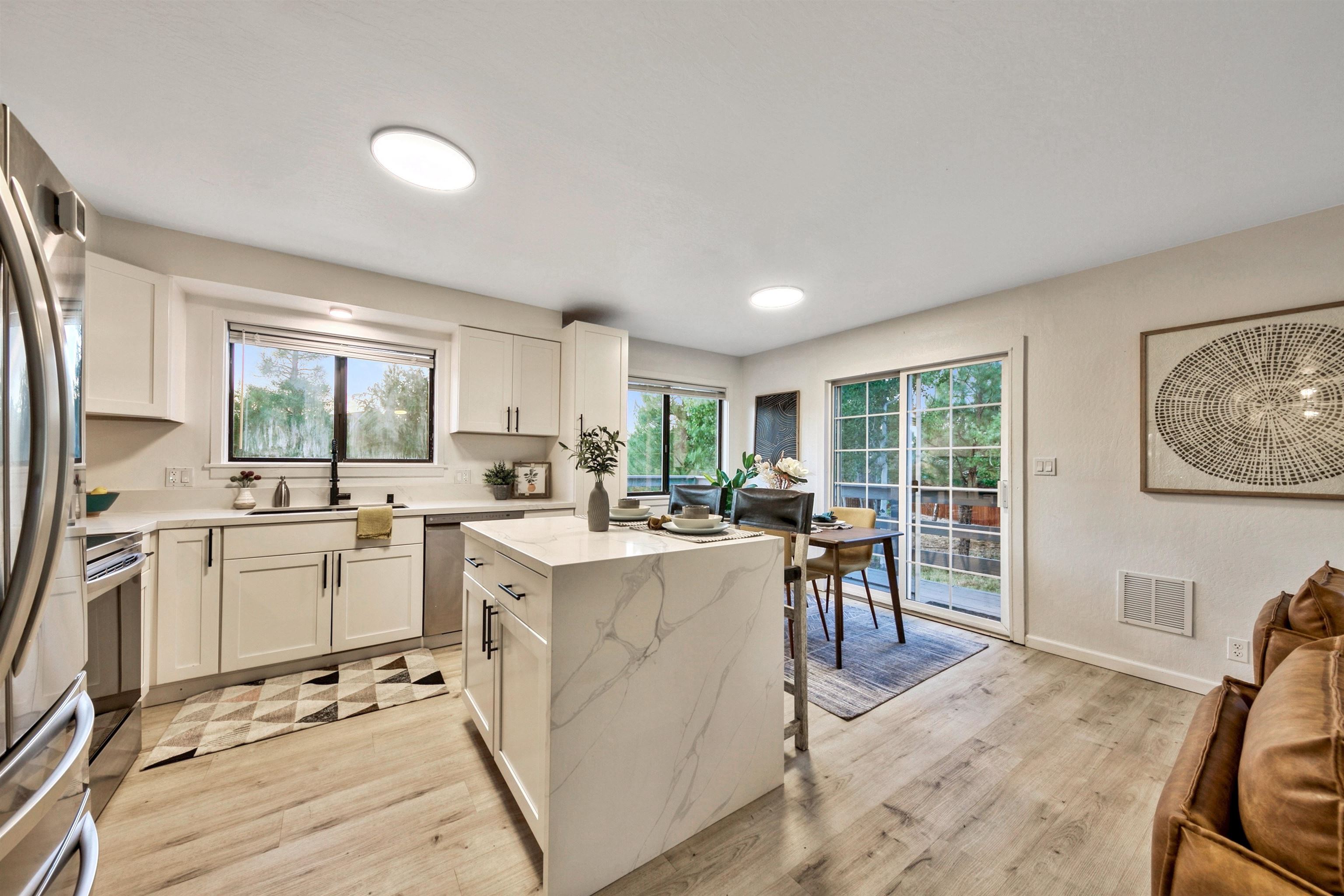 a kitchen that has a lot of white cabinets and stainless steel appliances