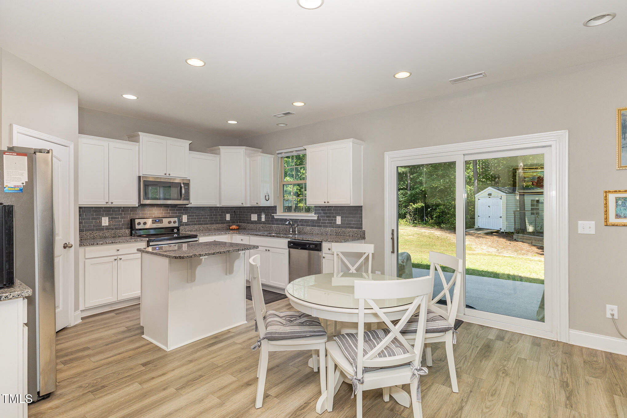 a kitchen with a dining table chairs and refrigerator