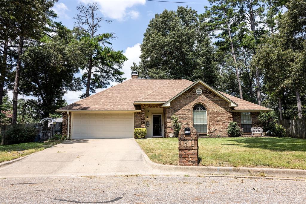 a view of a house with a yard and large tree