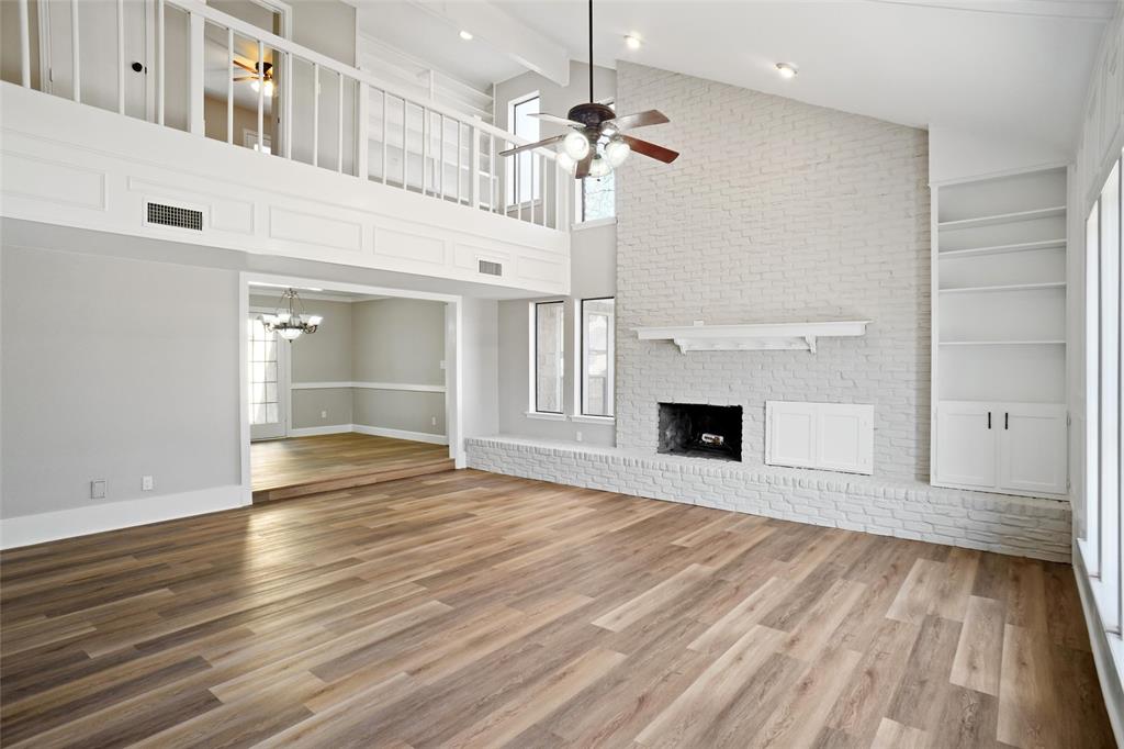 a view of an empty room with wooden floor fireplace and a window