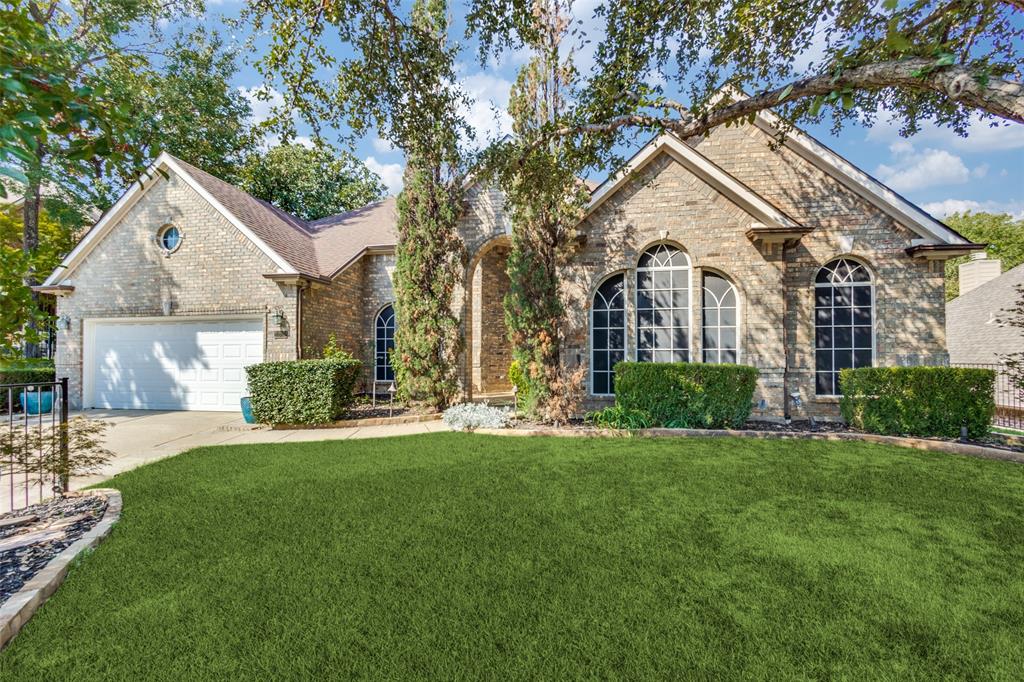 a view of a white house next to a yard with a big yard and large trees