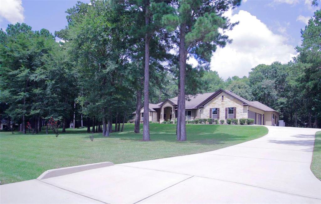 a view of house with a big yard plants and large trees