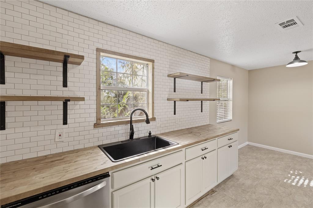 Kitchen with white cabinets, sink, and wooden counters