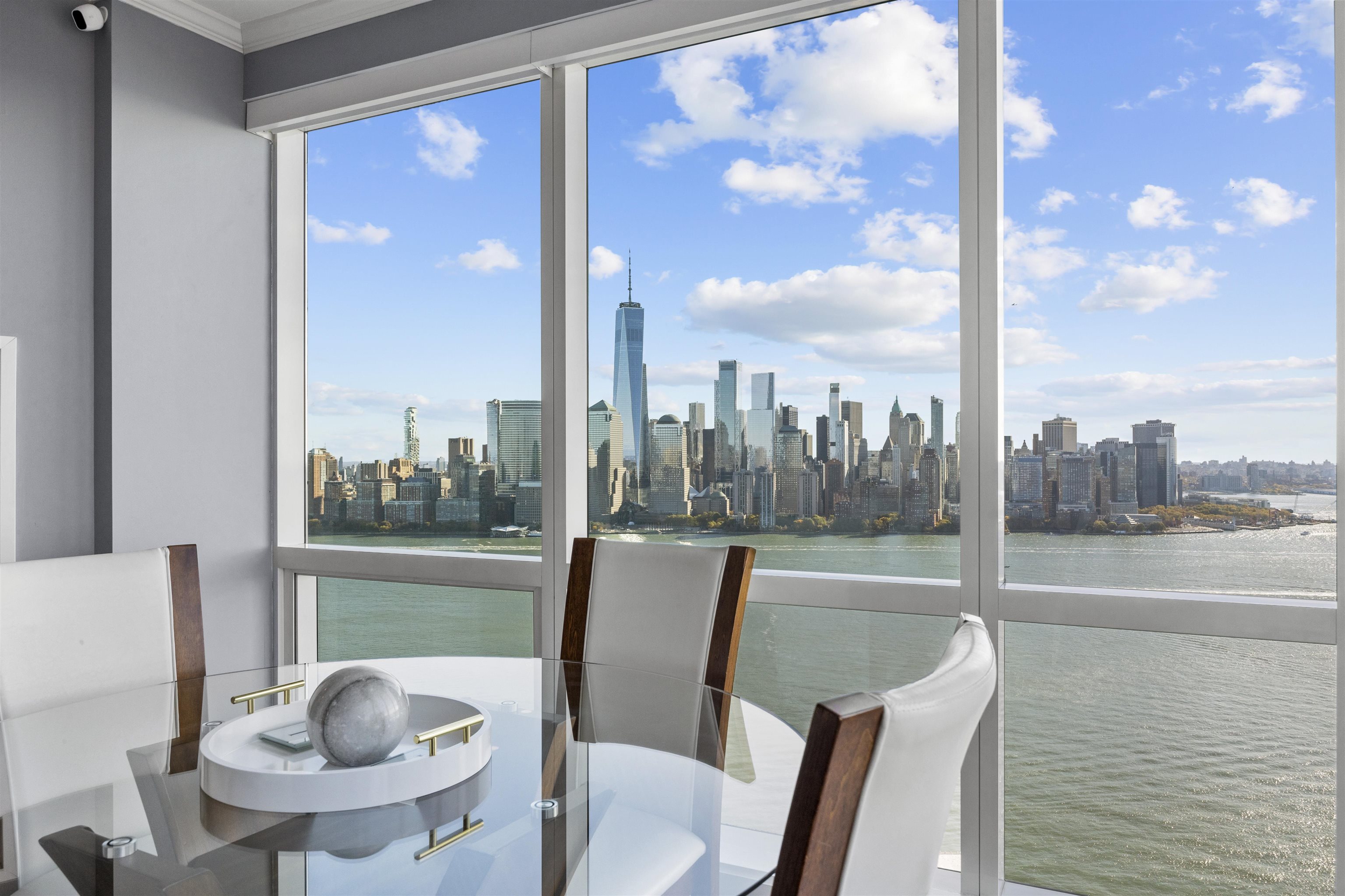 a view of a city from a dining room with furniture and a floor to ceiling window