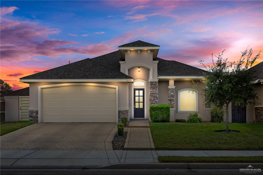 View of front of house with a yard and a garage